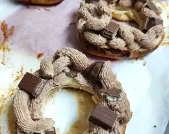 Step <p>Ponga los roscones sobre una rejilla colocada sobre una bandeja y con una cuchara, bañe los roscones con el glaseado. Decore con las barritas Kinder®, los huevos de chocolate y el crocanti de almendras (opcional). Ponga 2 barritas de chocolate blanco en una manga pastelera pequeña y fúndalo en el microondas. Decore con hilos de chocolate blanco, corte en porciones y sirva.</p> illustration