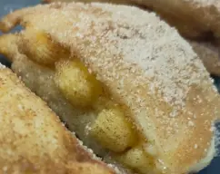 Step Vamos reyenando con la crema pastelera, y tapas con otro trozo de torrija, pasas por la canela, el azúcar y servimos. illustration