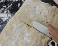 Step <p>Con la espátula, baje la masa hacia el fondo del vaso y amase 1 min/ espiga.</p><p>Vierta la masa sobre una superficie espolvoreada con harina, aplastela con las manos formando un cuadrado de 30x30.</p><p><br></p><p><br></p> illustration